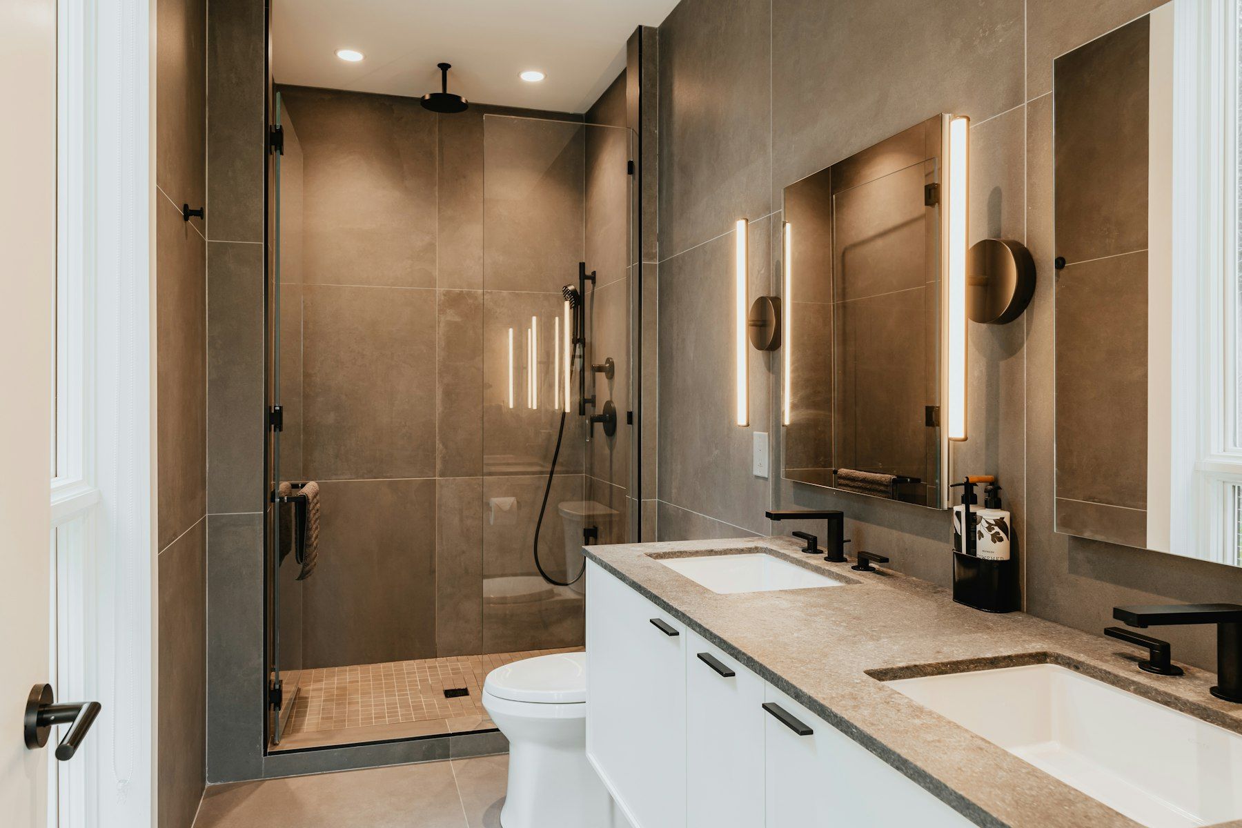 Baño en tonos tierra con ducha de obra y doble lavabo