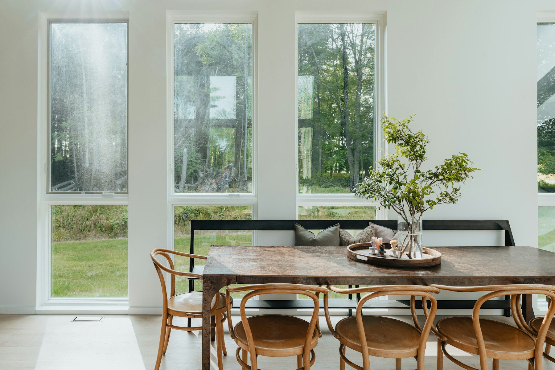 Comedor con sillas de madera curvada y ventanales al jardín
