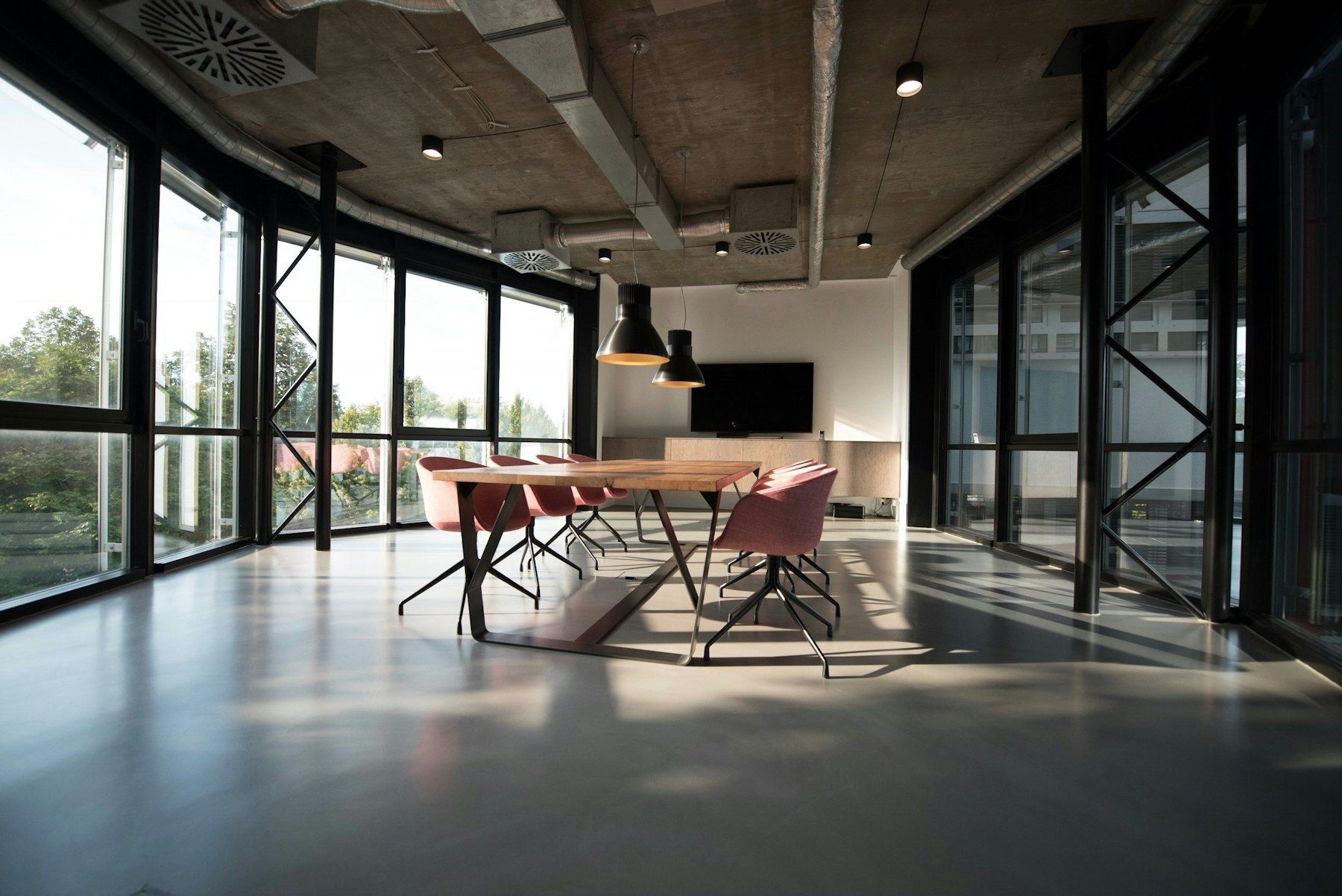 Oficina con techo de hormigón, ventanales y mesa de reuniones