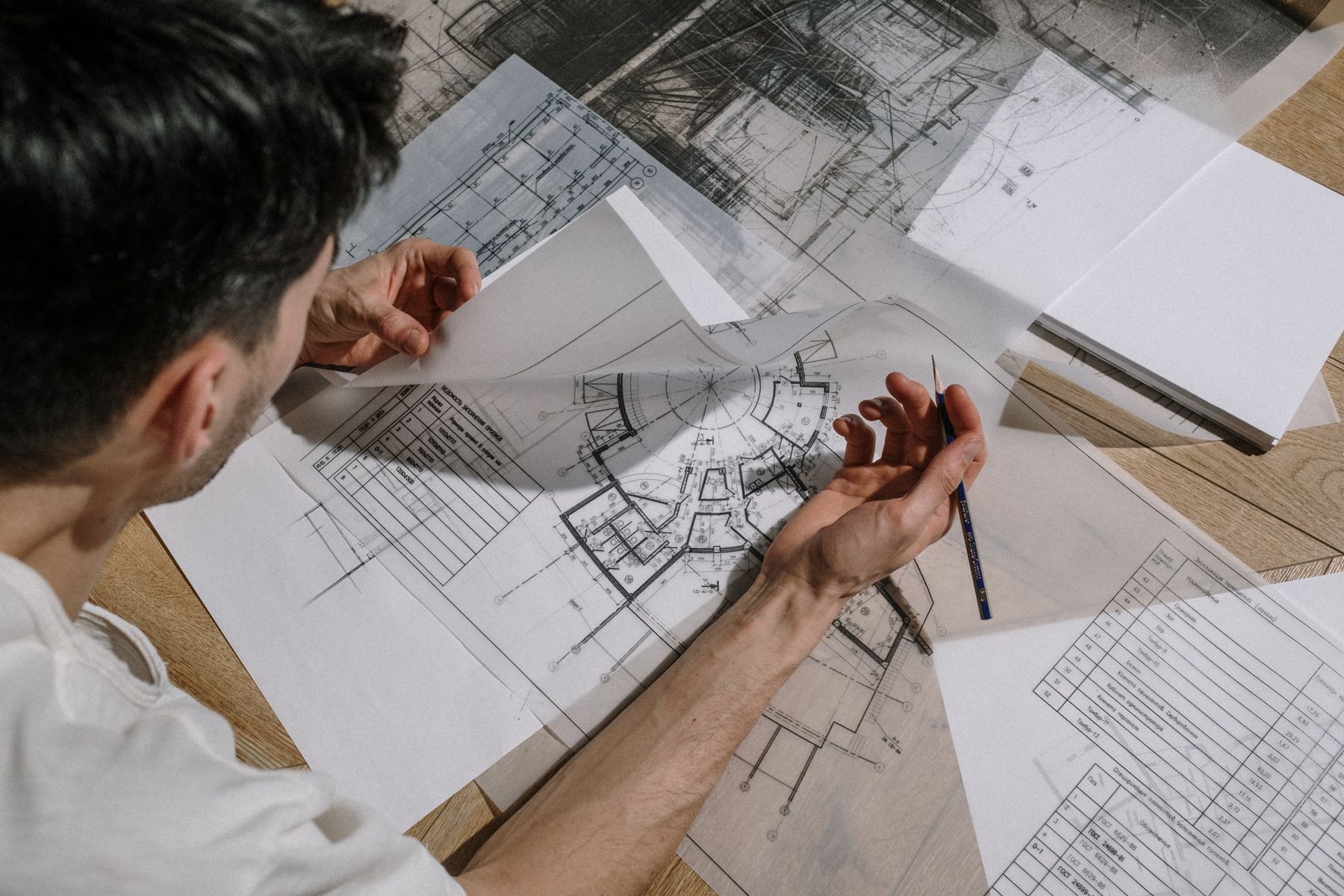 Profesional revisando planos de planta sobre una mesa de madera