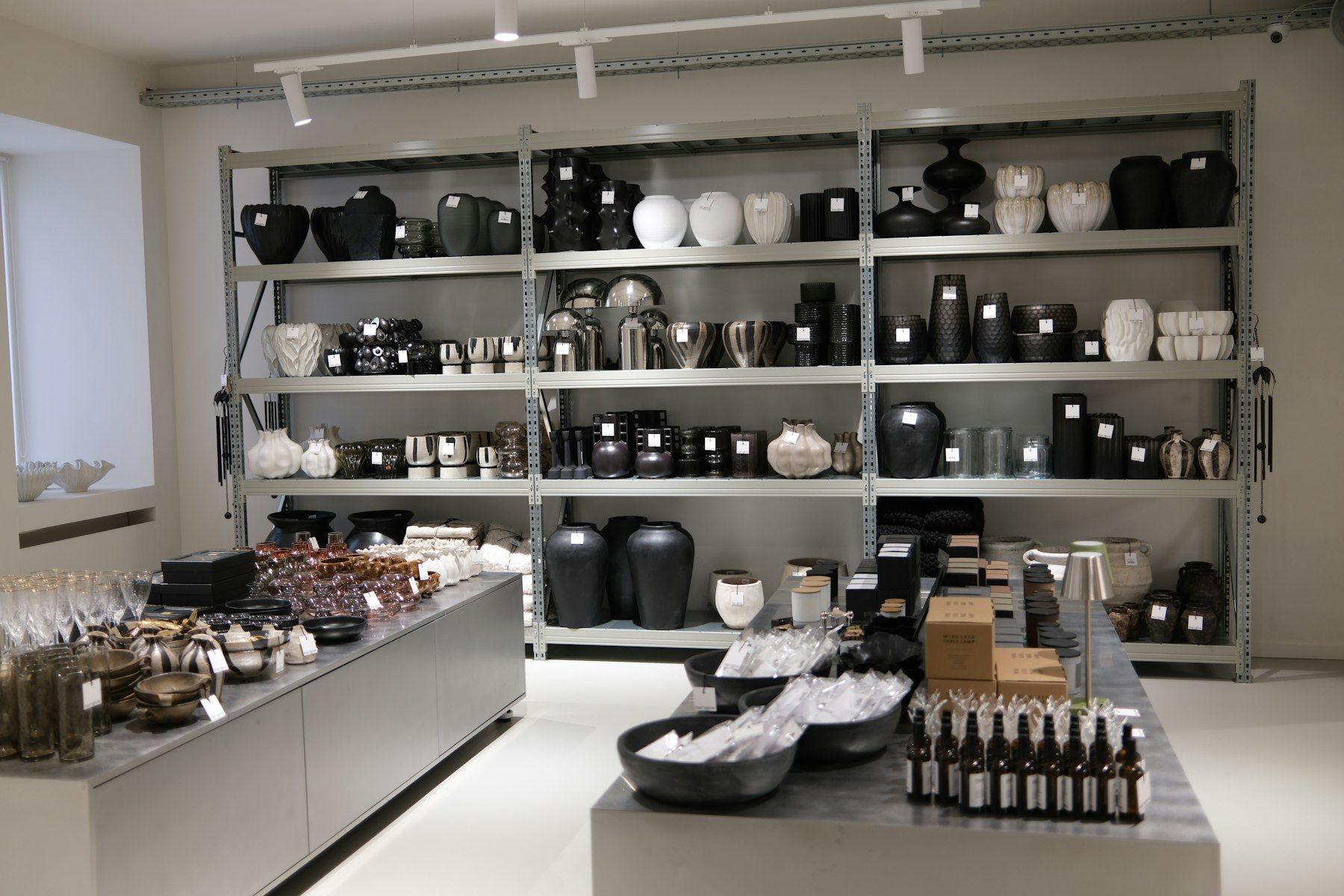 Tienda con estanterías metálicas, mesas expositoras y focos en carril