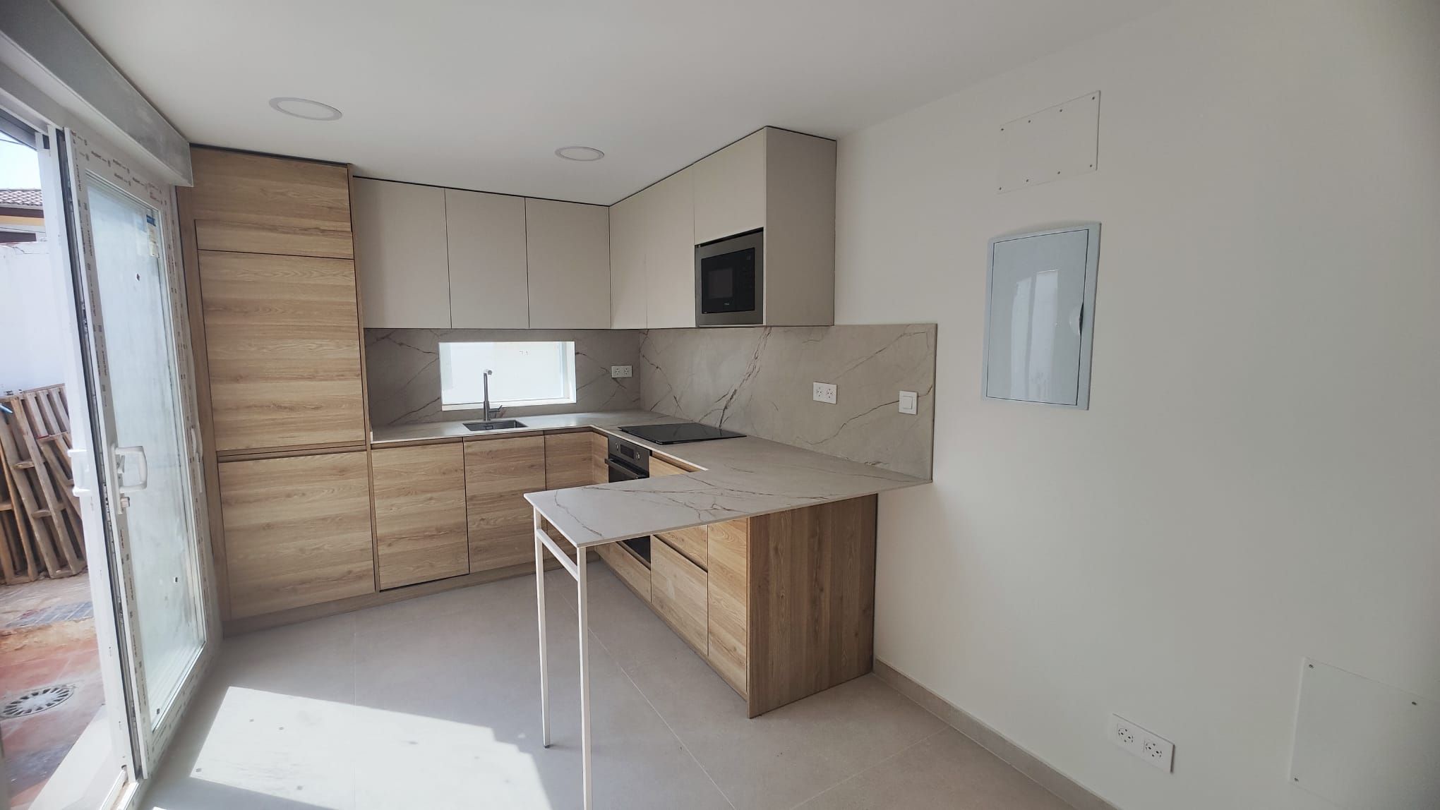 Cocina reformada por la empresa en la calle Princesa, con muebles de madera, península y salida al patio