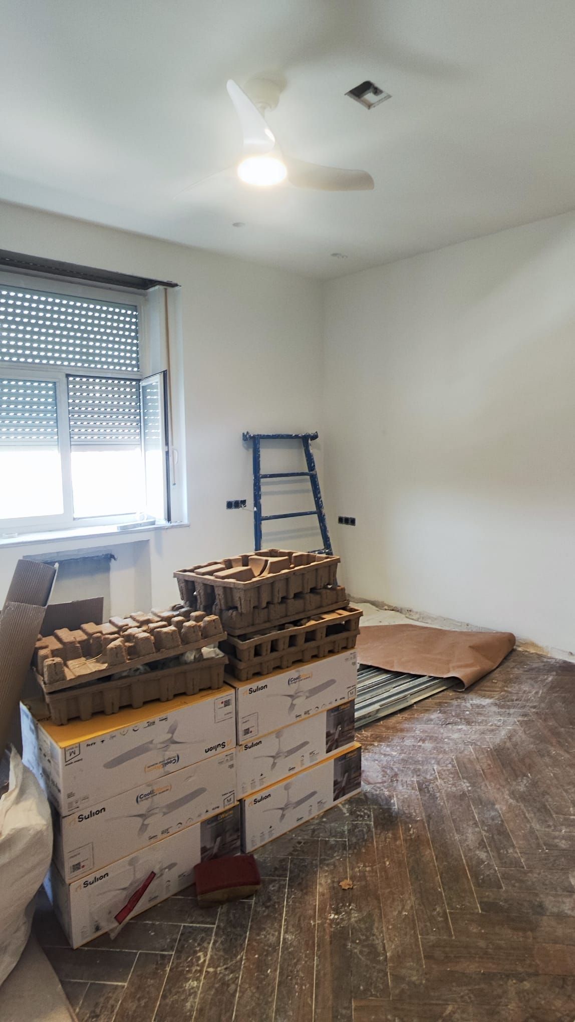 Dormitorio en obra con cajas de material y el suelo protegido