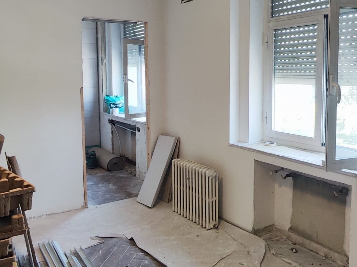 Habitación en obra con el suelo protegido, el radiador y la ventana con persiana