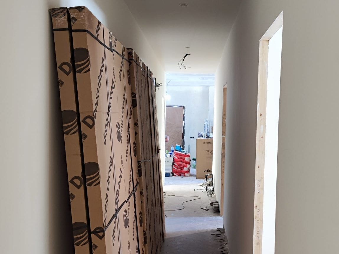 Pasillo en obra con el material nuevo embalado apoyado en la pared