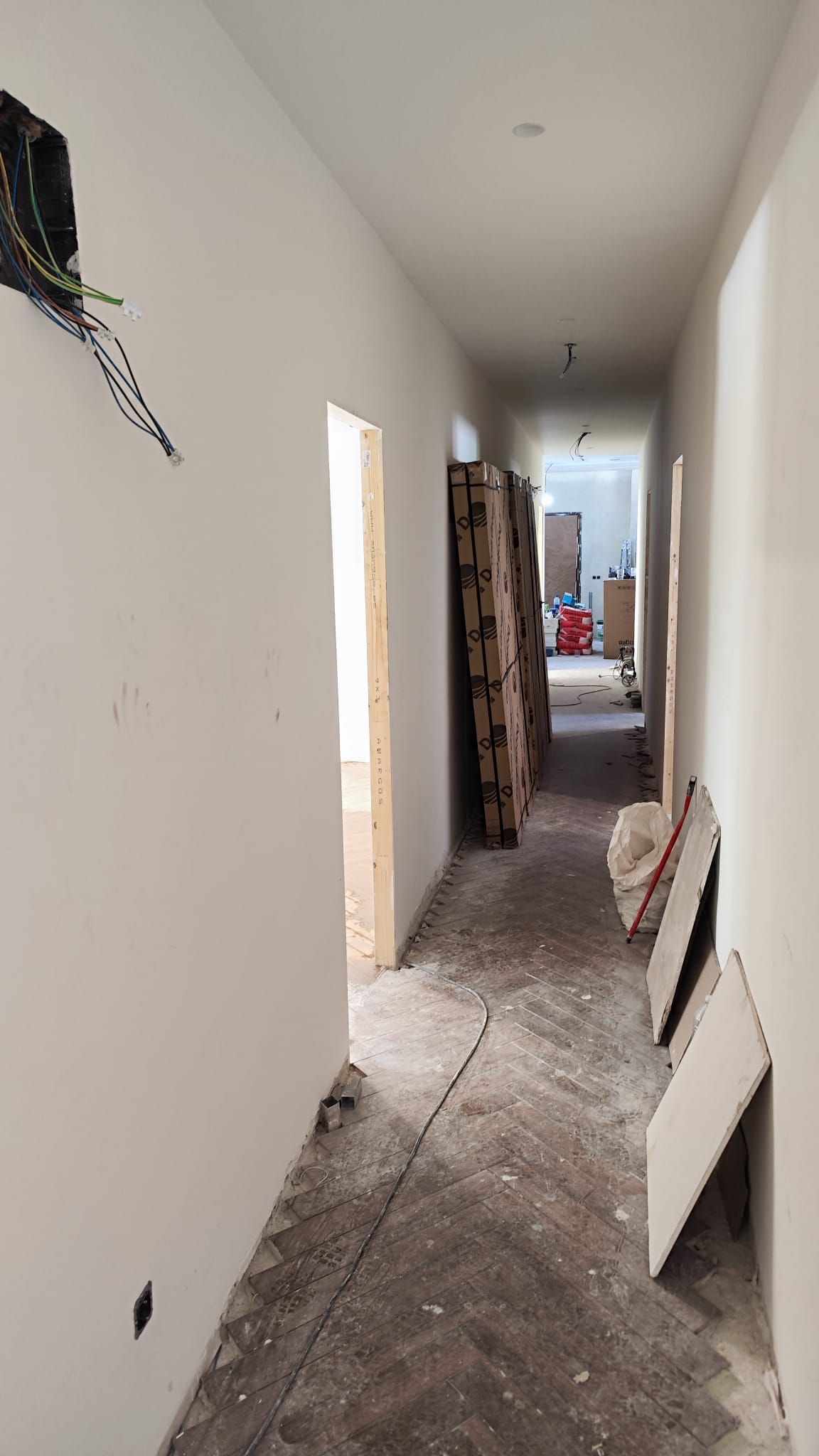 Pasillo del piso en obra, con las paredes preparadas y el cableado nuevo a la vista