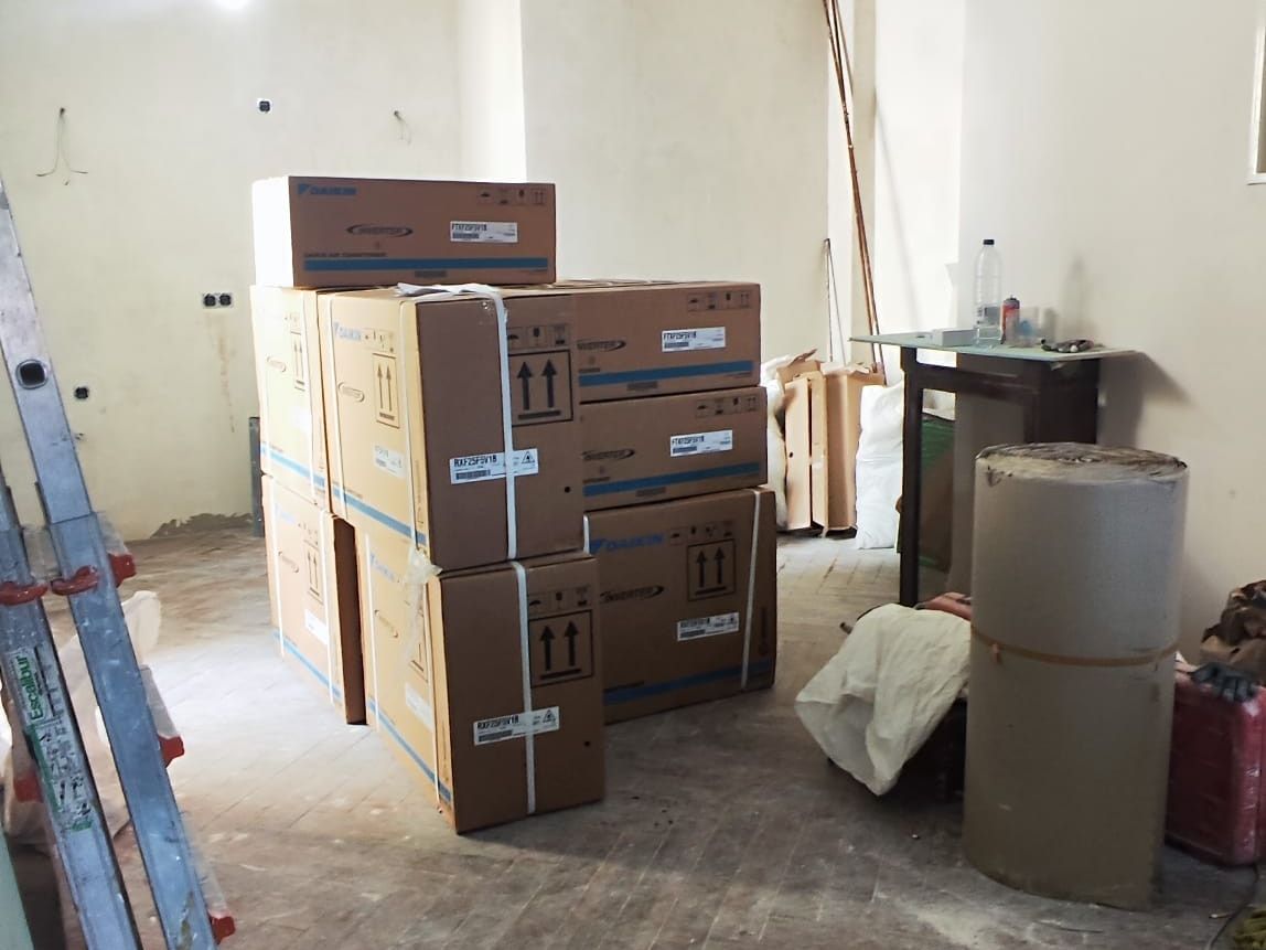 Salón en obra con el suelo de parqué en espiga y el material embalado