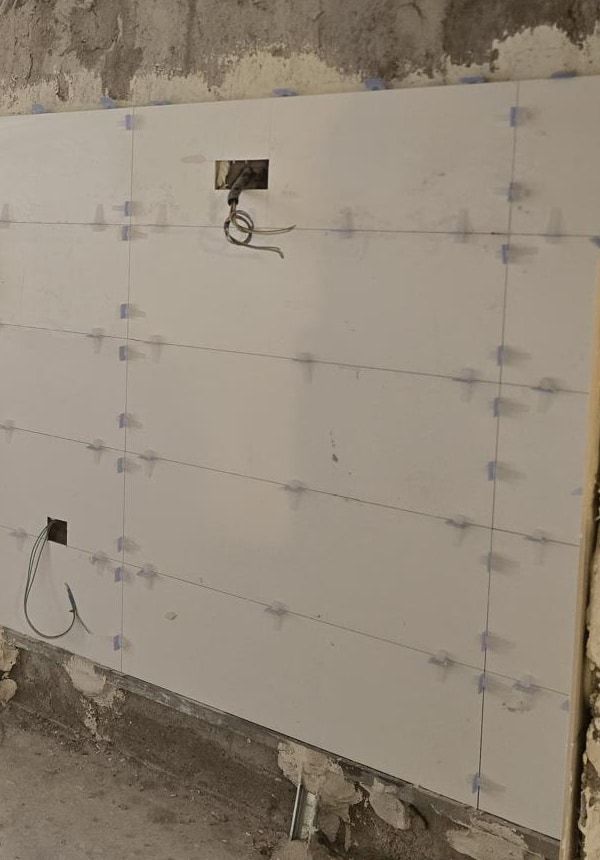 Detalle del alicatado de la cocina: piezas blancas de gran formato con el sistema de nivelación y las cajas eléctricas
