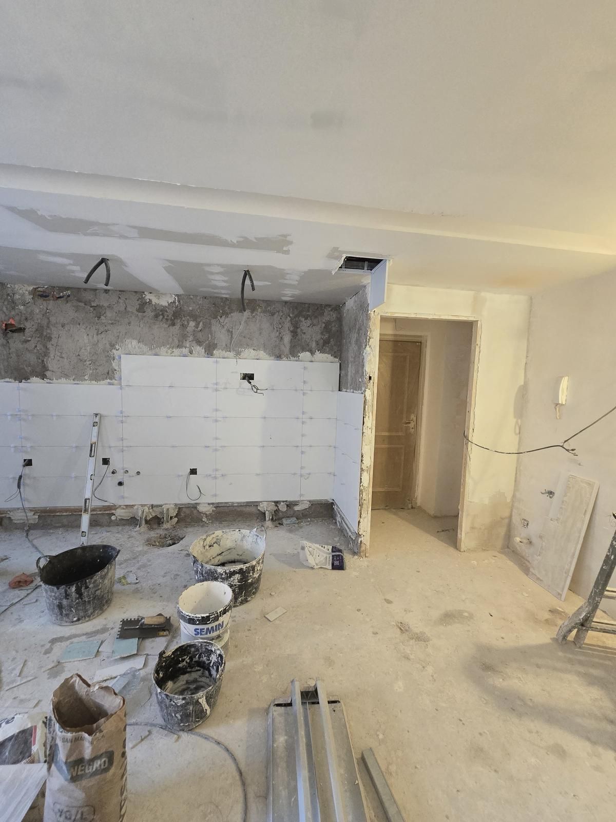 Cocina en obra con el alicatado blanco en la pared de trabajo y el falso techo de placa de yeso
