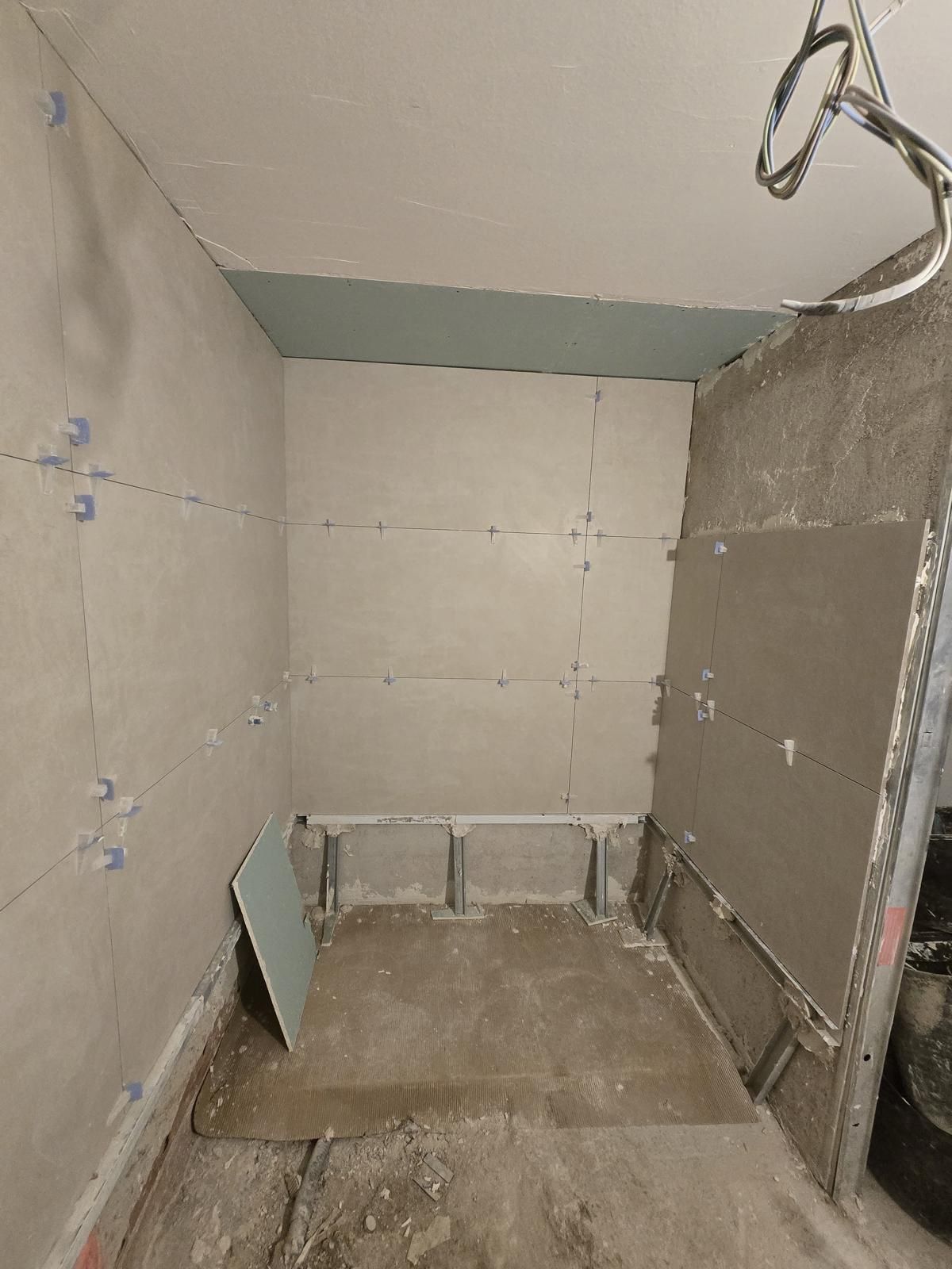 Zona de ducha en obra, alicatada hasta el techo con placa resistente a la humedad