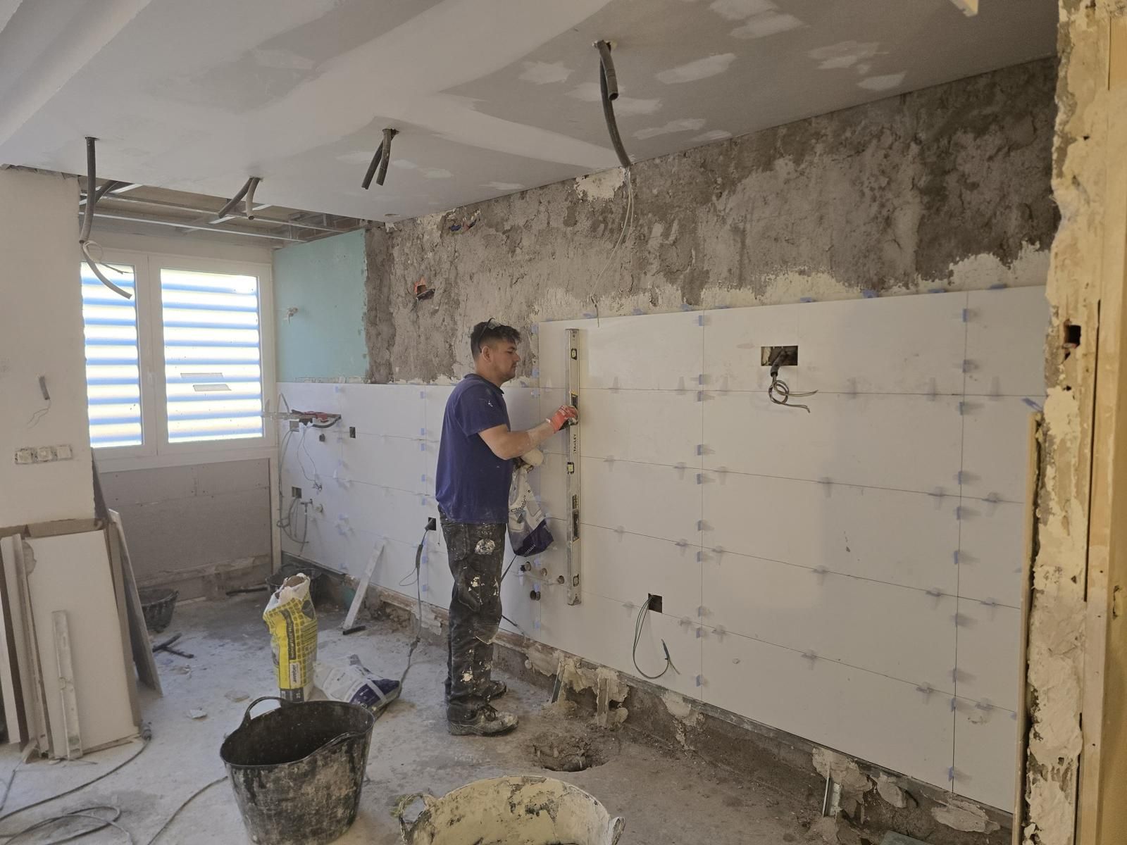 Operario nivelando el alicatado de gran formato de la cocina con sistema de nivelación