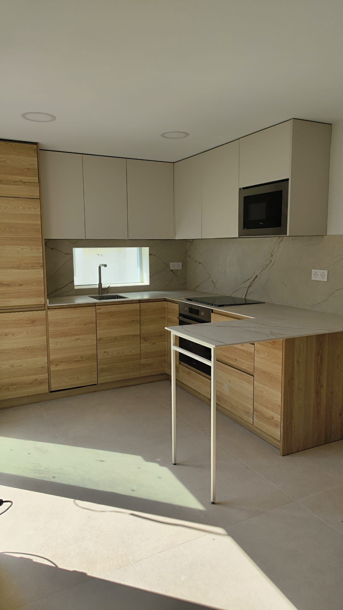 Frente de la cocina con ventana sobre el fregadero y columna de horno y microondas