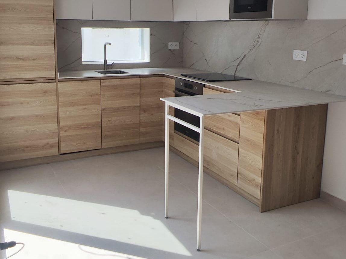 Cocina en L con columna de horno y microondas, fregadero bajo la ventana y suelo de gran formato