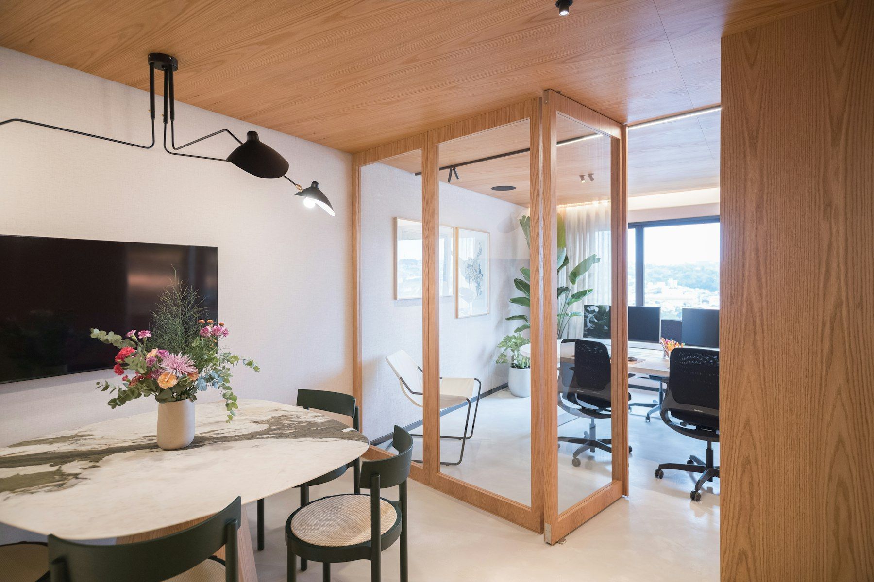 Sala de reuniones con mesa de piedra y cerramiento de vidrio y madera hacia la zona de trabajo