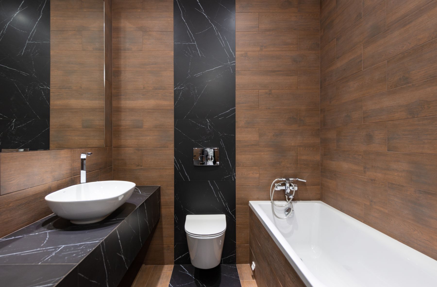 Baño con paredes de madera y mármol negro y lavabo sobre encimera