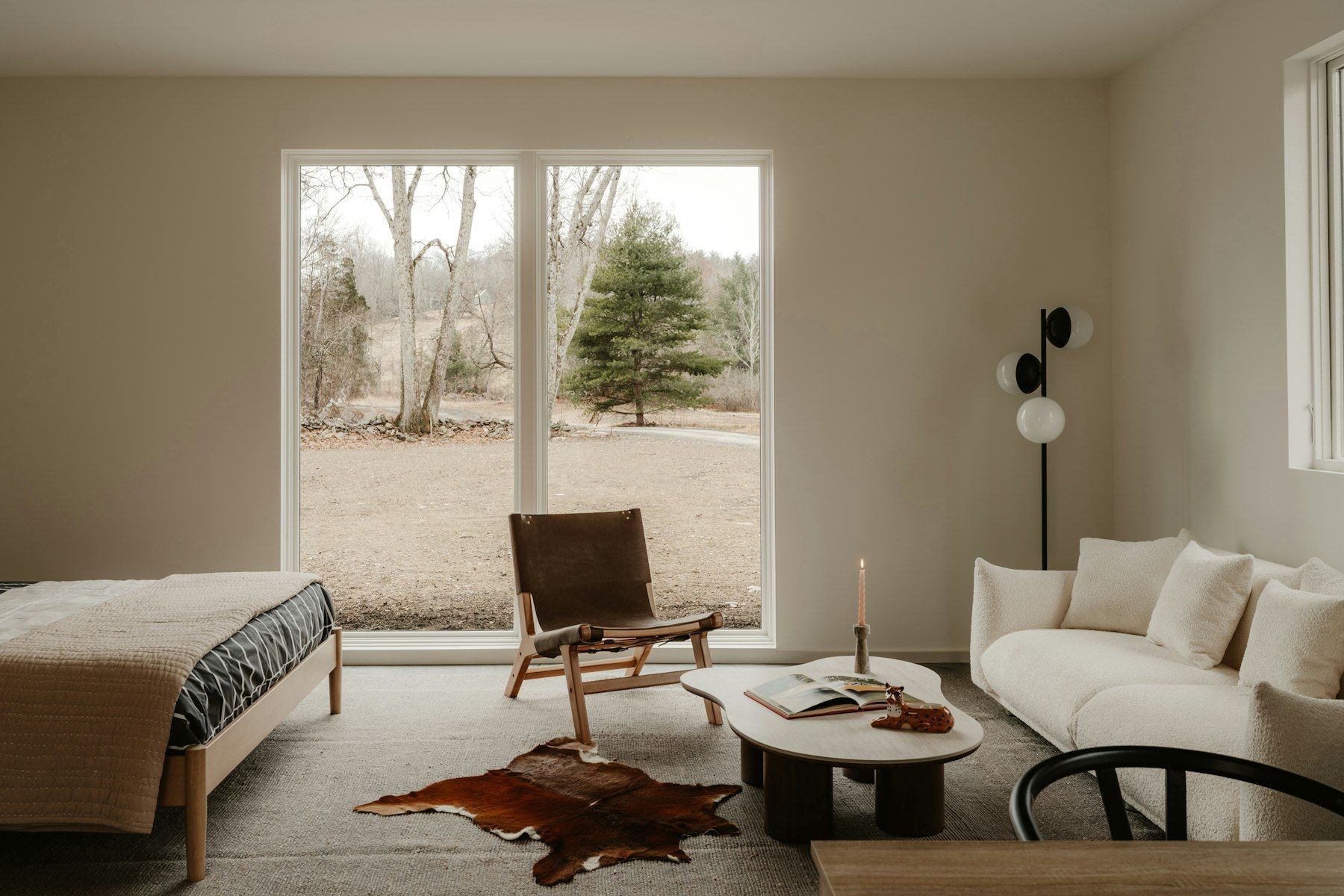 Sala con ventanal al jardín, sofá y sillón de madera