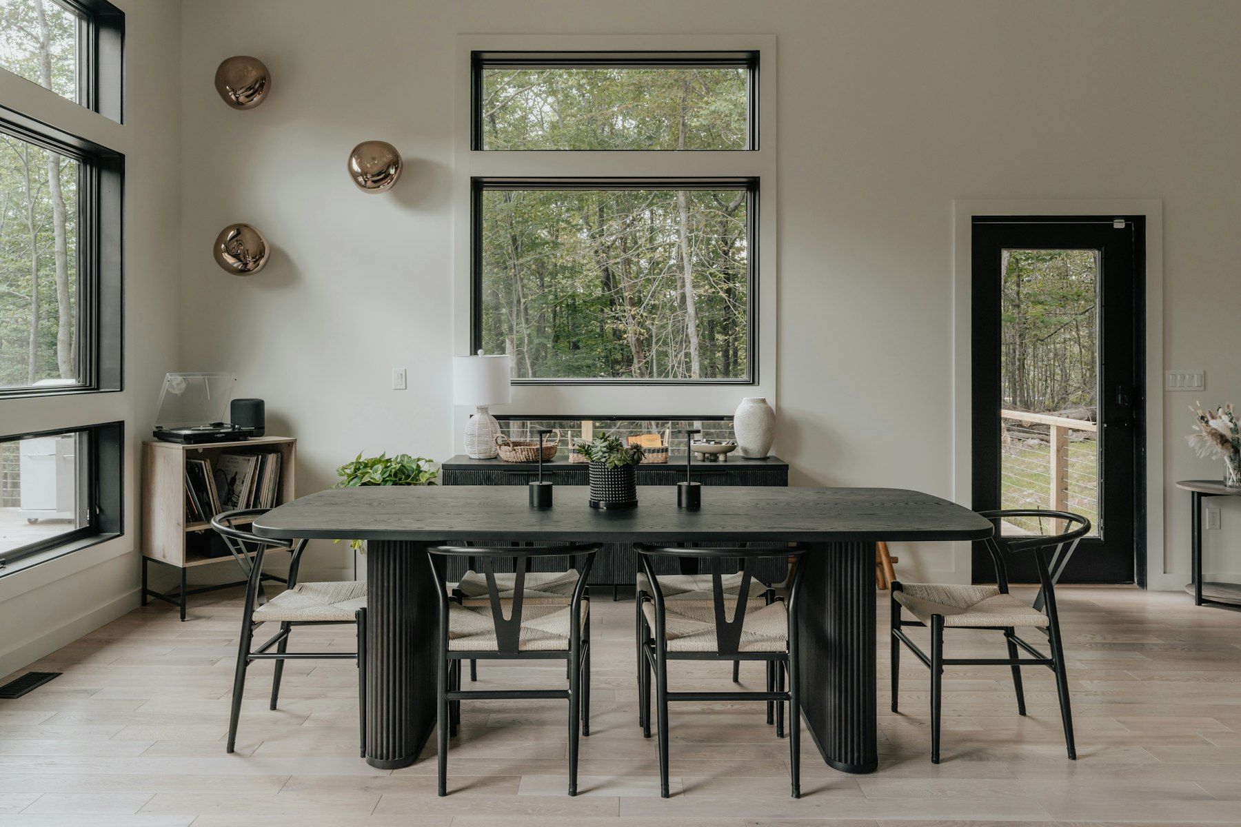 Comedor contemporáneo con mesa oscura y grandes ventanas