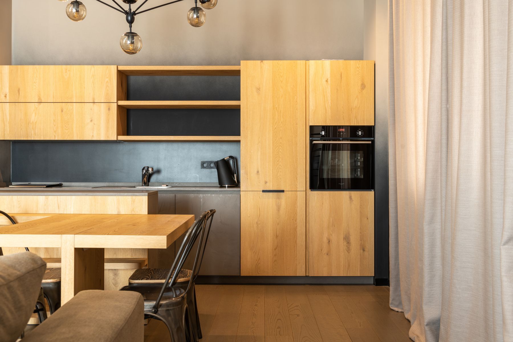 Cocina de roble con columnas de horno y mesa de comedor
