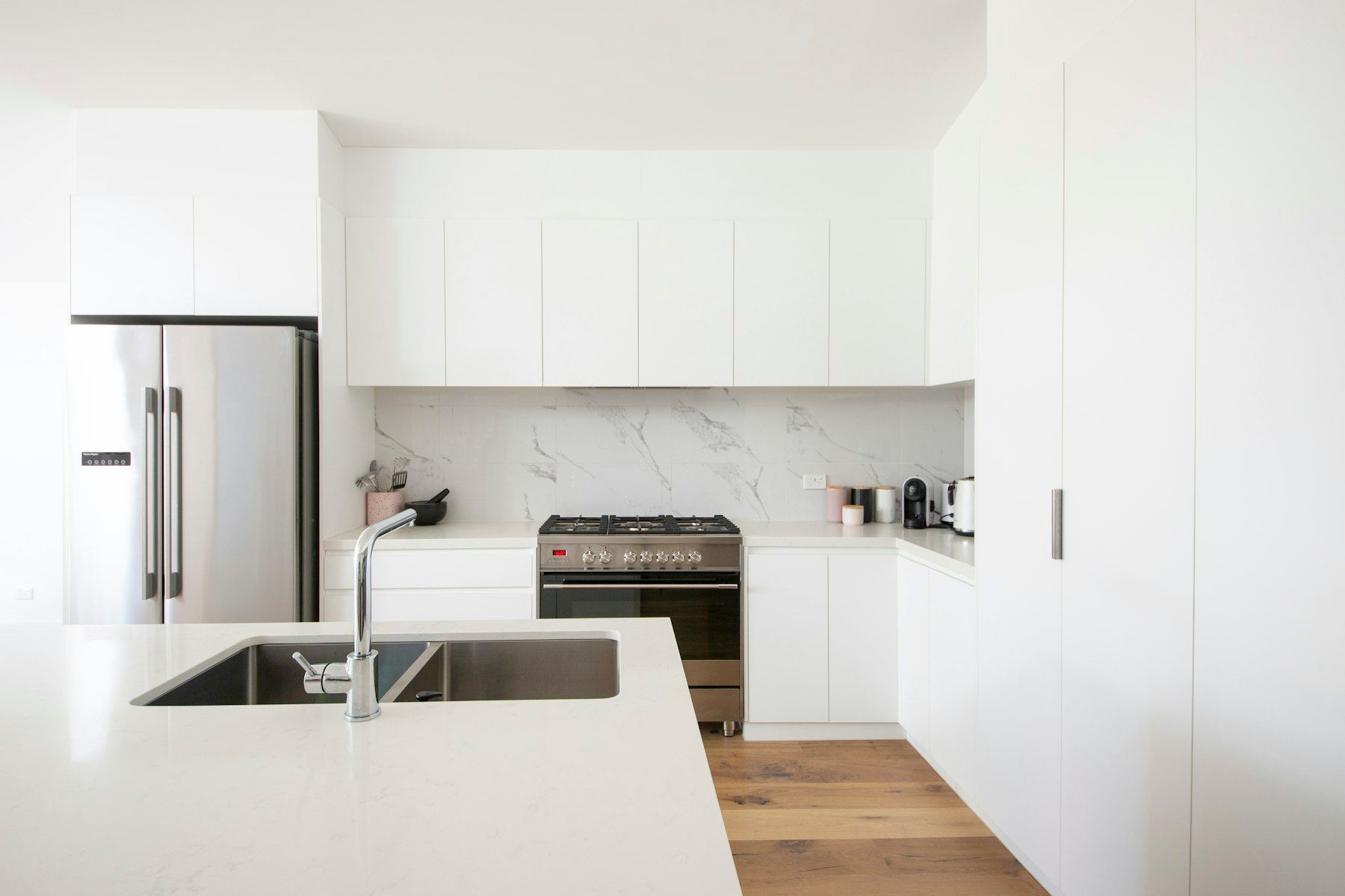 Cocina blanca sin tiradores con isla y fregadero